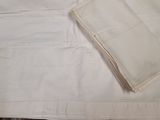 a piece of white cloth on the table next to a folded napkin
