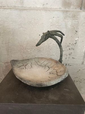 a sculpture of a bird sitting on top of a bowl
