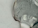 a silver spoon with a bird on it sitting on a table