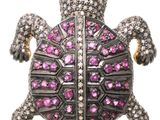 un gros plan d'un pendentif en forme de tortue orné de pierres roses sur fond blanc