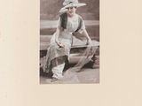 une vieille photo d'une femme assise sur un banc, coiffée d'un chapeau