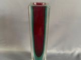 un vase en verre rouge et vert posé sur une table
