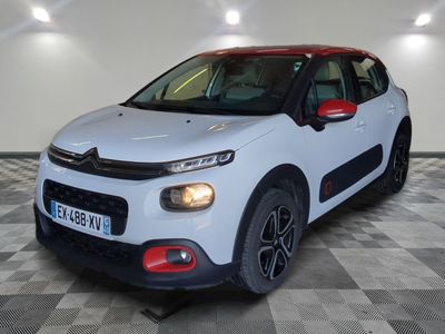 une voiture blanche de marque Citrole garée sur un sol à damier dans un garage