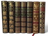 six vieux livres sont alignés sur une surface blanche