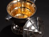an image of a silver bowl with a lid on a black surface