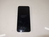 a black samsung phone sitting on a white table