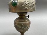 a silver vase with a green glass on top of it