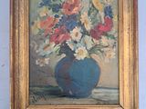 un tableau représentant des fleurs dans un vase bleu accroché au mur