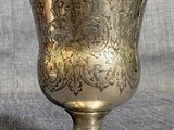un vase en argent posé sur une table, sur fond gris