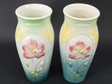 two vases with flowers painted on them on a black background