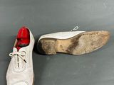 a pair of white shoes with red soles sitting on a gray surface
