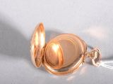 a gold pocket watch with a chain on a white surface