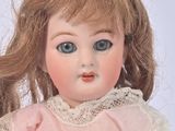 a doll that is wearing a pink dress with a lace collar