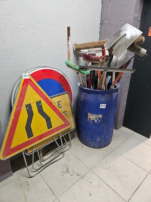 une poubelle et un panneau posé par terre à côté de la poubelle
