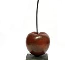 sculpture of an apple on a block with a leaf sticking out of it
