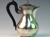 a silver coffee pot with a black handle on a table