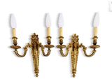 three brass wall sconces with candles on each of them