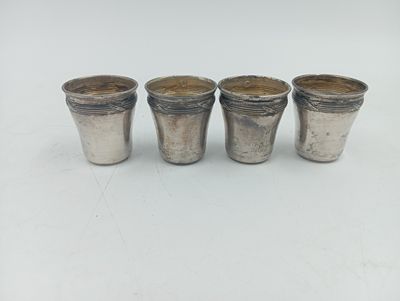 quatre verres à shot en argent posés sur une table blanche