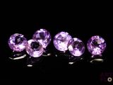 des pierres précieuses améthorates violettes alignées sur une surface noire