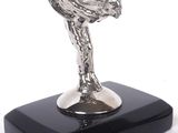 silver statue of a woman holding a bird on a black base