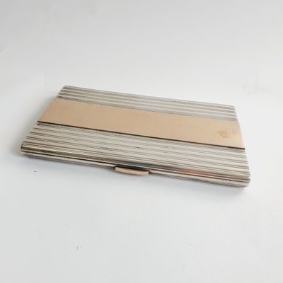 a silver and gold business card case on a white table