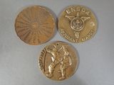 three gold medals are shown on a table with a white background