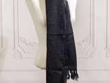 the black scarf is hanging on a mannequin in front of a white wall