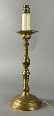 a brass table lamp with a white candle on top of it