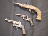 three old guns are sitting on a black cloth on a table