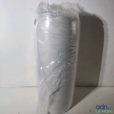 un rouleau de plastique emballé dans du plastique posé sur une surface blanche