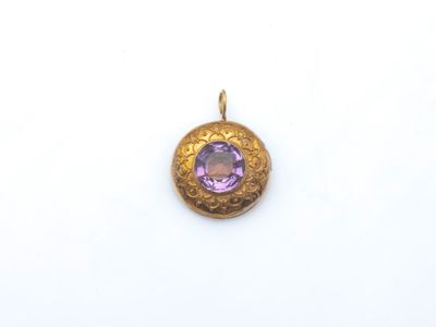 un gros plan d'un pendentif en or orné d'une pierre violette