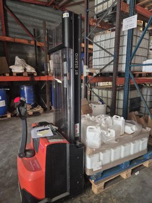 un chariot élévateur transportant une palette remplie de conteneurs blancs