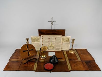 une table en bois sur laquelle se trouvent une croix, un livre, une bougie et d'autres objets