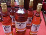 six bouteilles d'alcool sont alignées sur une nappe rose