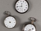 Trois types différents de montres de poche sont exposés sur un fond gris