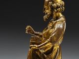a bronze statue of a man holding a book