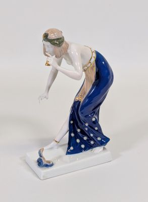 une figurine représentant une femme qui se penche pour ramasser quelque chose