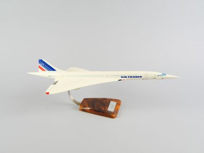 une maquette d'avion posée sur un socle en bois, sur fond blanc
