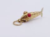 an image of a gold fish charm with a red bead on it