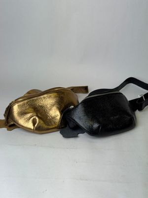 two black and gold fanny bags sitting next to each other on a white surface