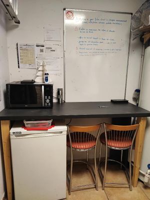 a small kitchen with a refrigerator, microwave, and two chairs
