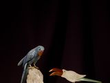 two figurines of birds sitting on top of a rock