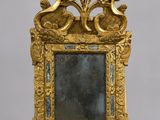 un cadre doré richement décoré, avec un miroir au centre