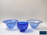 trois bols en verre bleu posés les uns à côté des autres sur une surface blanche