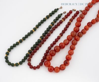 trois colliers composés de perles rouges et vertes sur un fond blanc