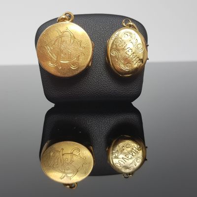 un gros plan sur une paire de boucles d'oreilles en or posées sur une surface noire