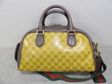 yellow and brown guccissi handbag sitting on top of a white table