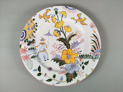une assiette décorée de fleurs et d'oiseaux, posée sur une table