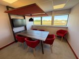 une photo d'une salle de réunion avec une table et des chaises rouges