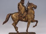bronze statue of a man riding a horse with a gun